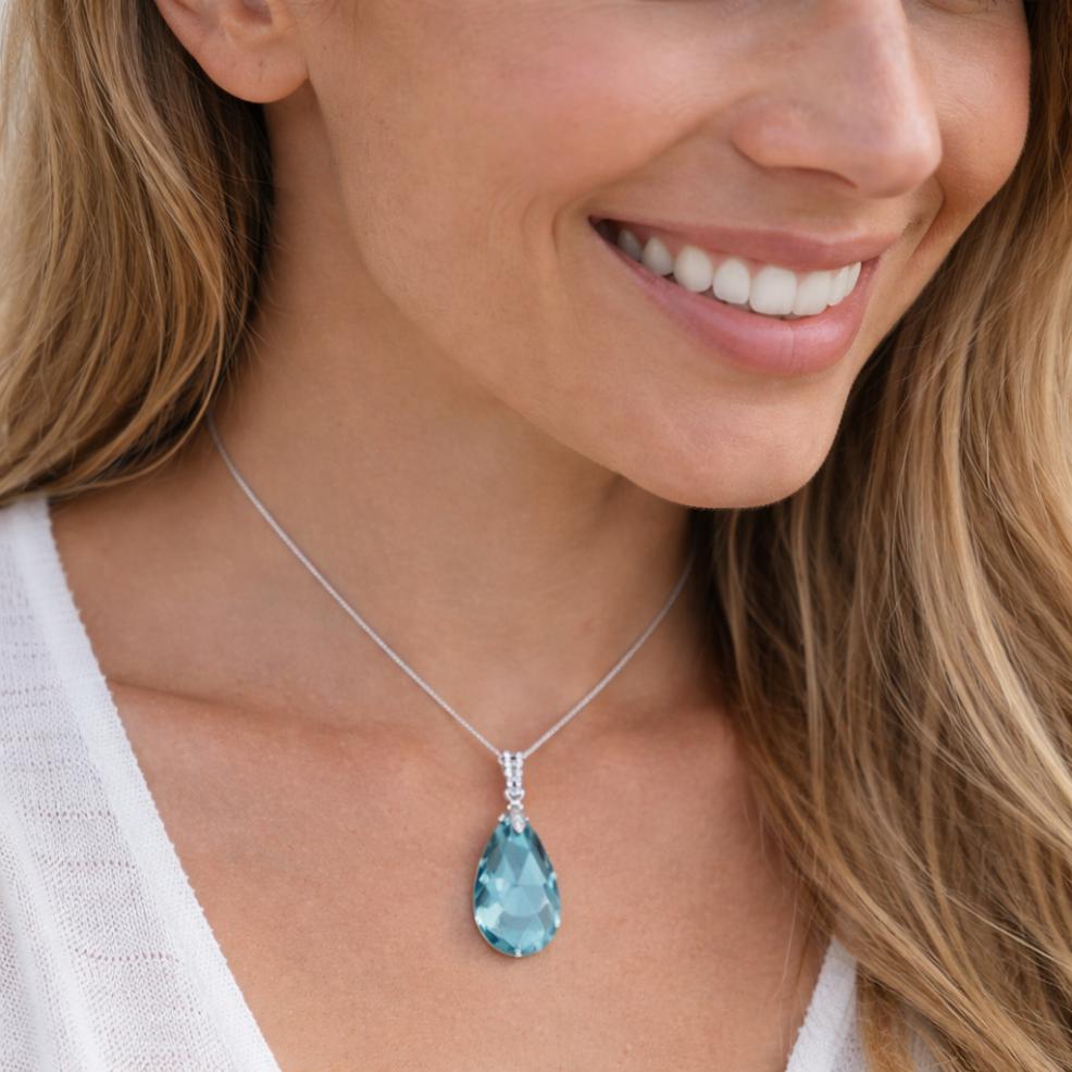 Woman wearing a necklace with a blue teardrop pendant