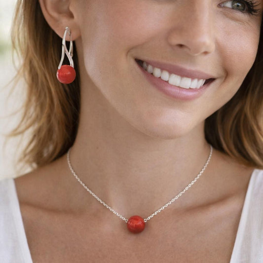 silver necklace with a red pendant and matching earrings.