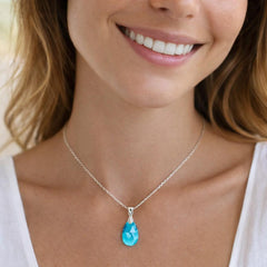 silver necklace with a blue teardrop pendant