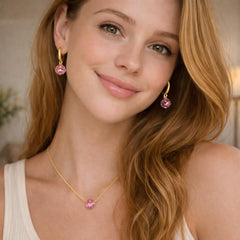 pink earrings and a gold necklace with a pink gemstone.
